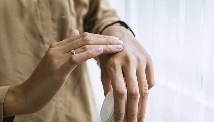 Eine Frau schmiert sich mit Creme die Hand ein