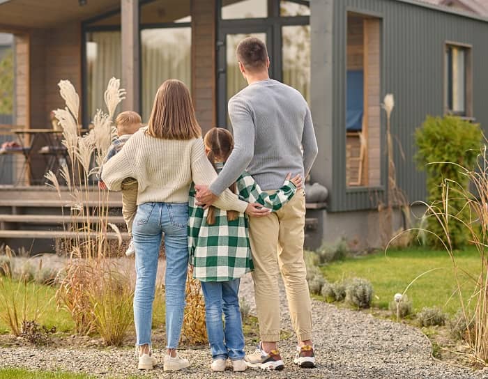 Eine Familie steht mit zwei Kindern vor einem neuen Haus