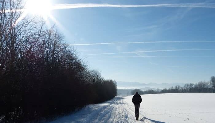 Ein Mann geht bei strahlender Sonne im Schnee spazieren