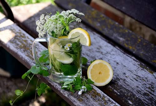 Ein Glas mit Kräuterlimonade steht auf einem Holztisch